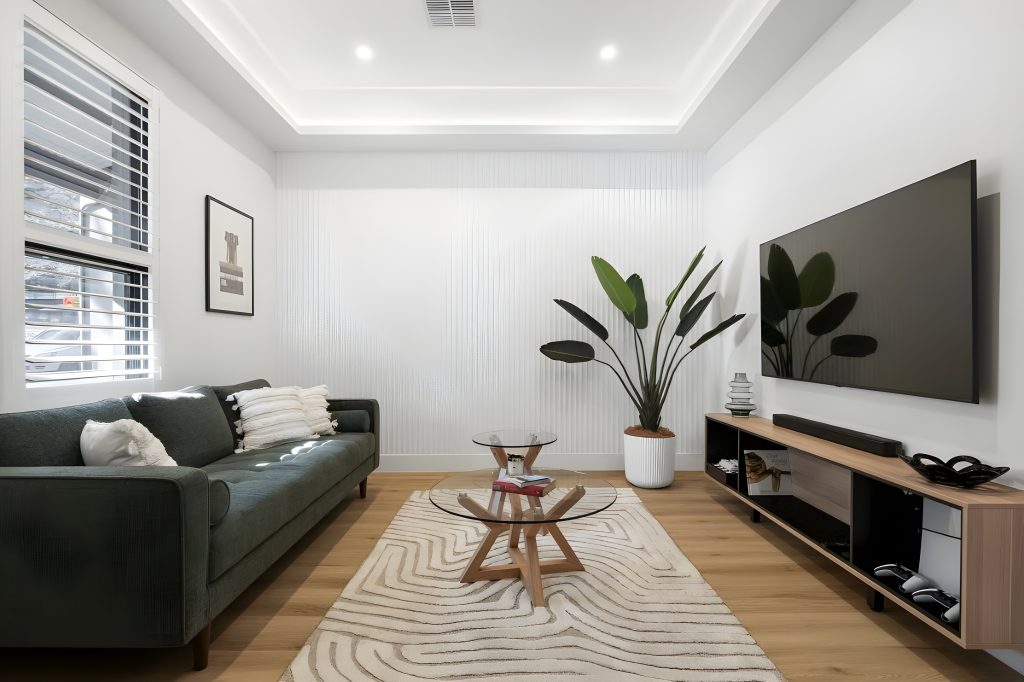 Living room with a dark sofa, glass coffee tables and television