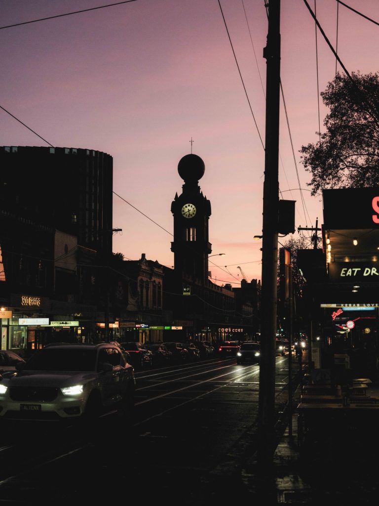Clock tower, shopfronts and traffic on Swan Street in Richmond at dusk
