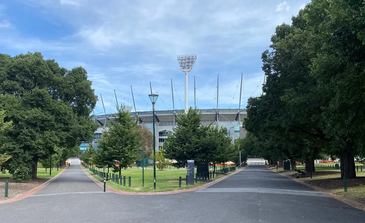 Melbourne Cricket Ground viewed across the paths and trees of Yarra Park